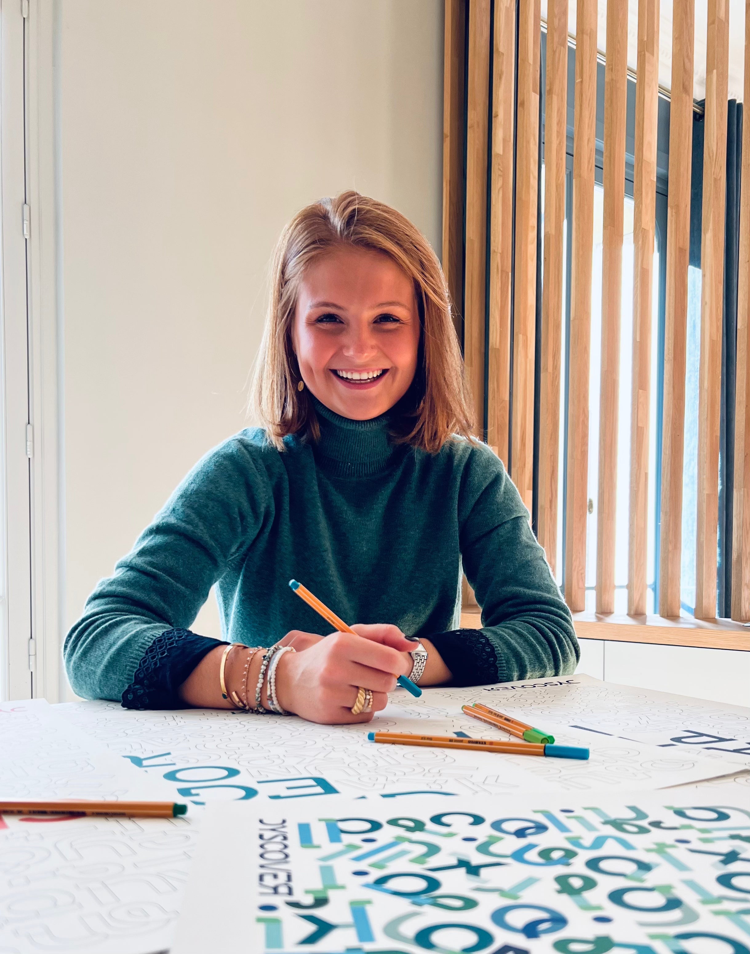 Fondatrice qui pose avec ses affiches avec un stylo à la main pour les colorier